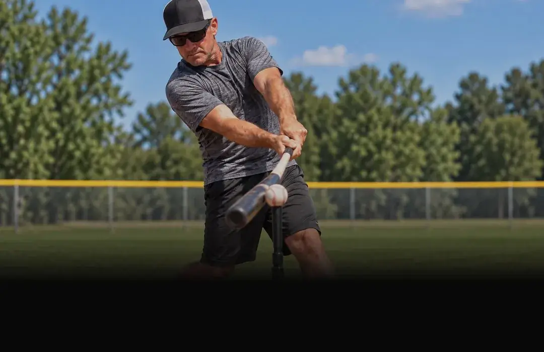 Hitter driving a ball off the tee on a baseball field